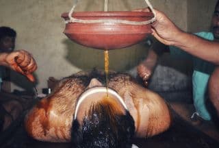 Warm herbal oil flowing during a Shirodhara treatment
